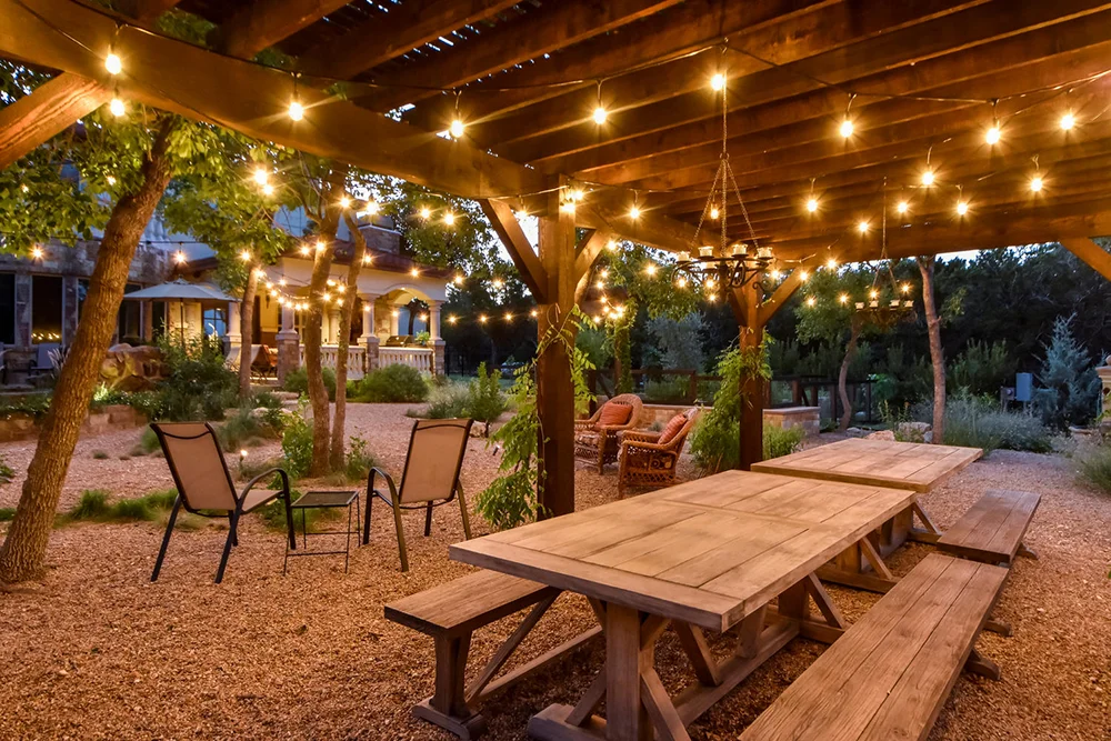 An outdoor table set under a pergolar with hanging lights