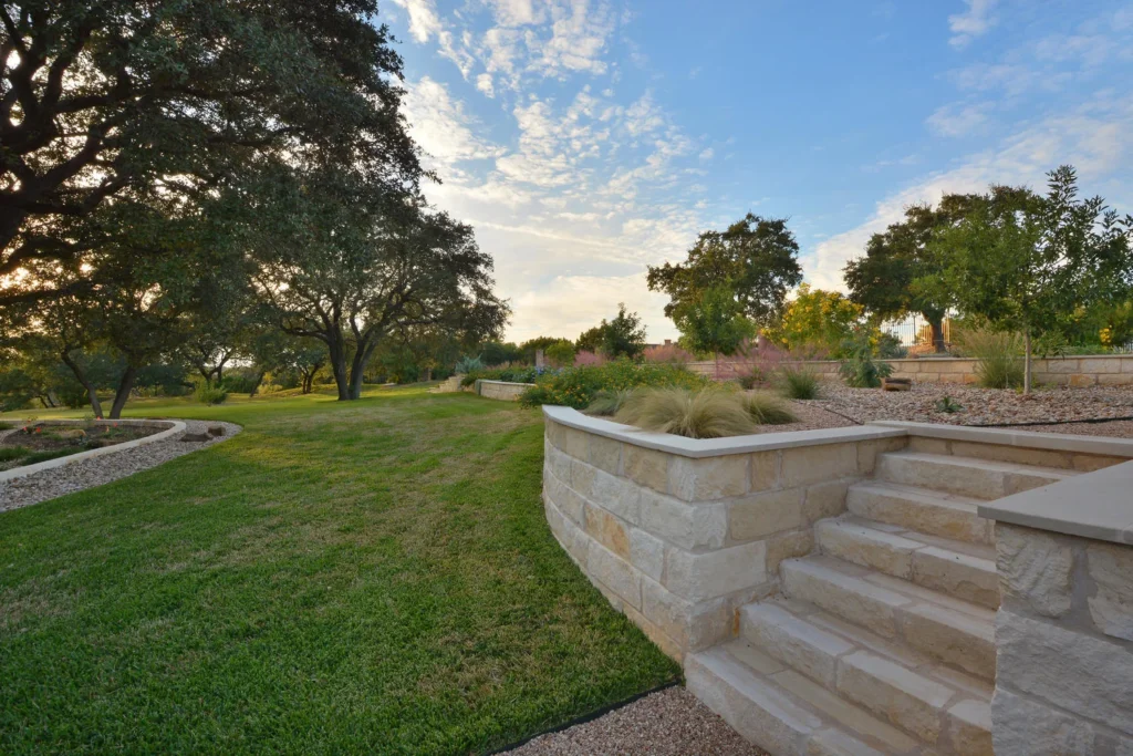 A large lawn with a stone wall and stairway on the right