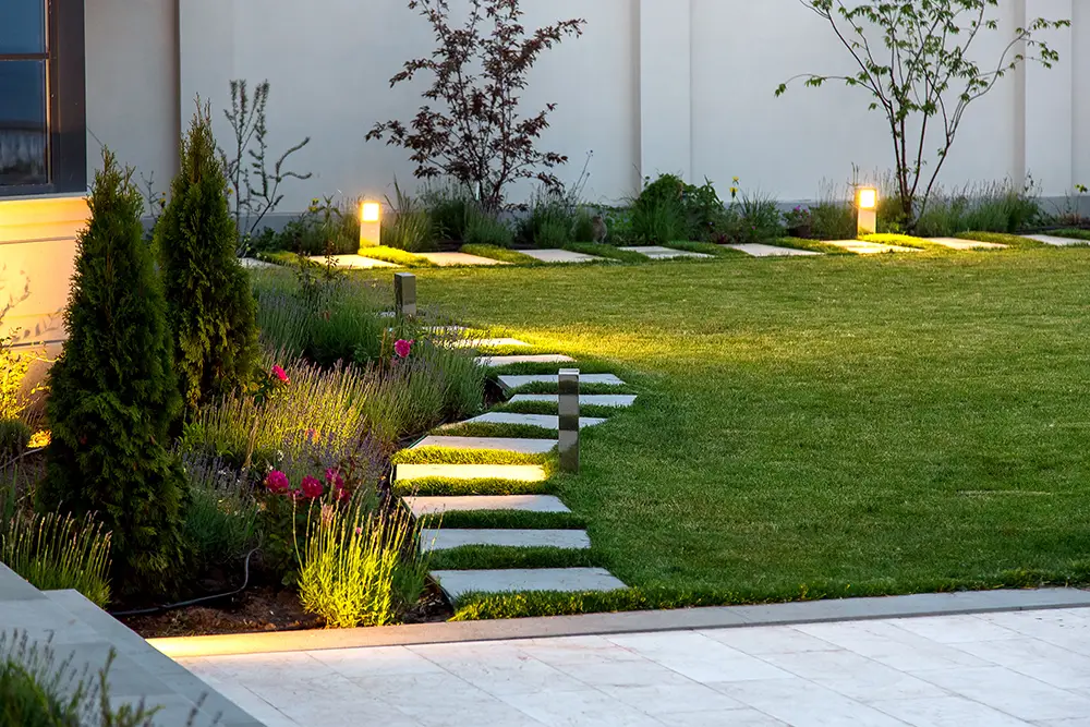 backyard with a flowerbed and a lawn of green grass as part of outdoor lighting design in Central Texas