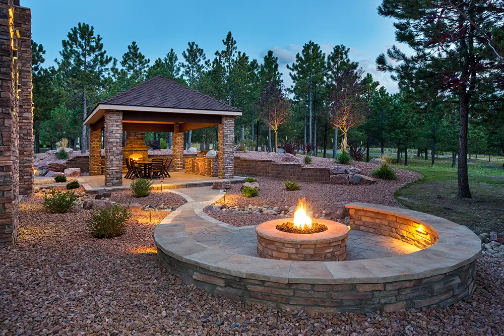 outdoor living space with gravel, firepit, stone seating, and pavilion